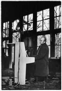 351047 Afbeelding van beeldend kunstenaar en muzikant Peter Schräder achter de piano in een uitgebrand schoolgebouwtje ...